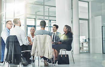 Image of employees sitting in a circle in backed chairs